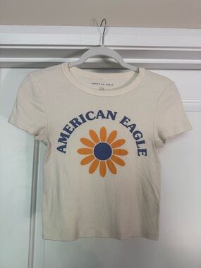 American Eagle Cream Tee with Blue Logo and Orange Daisy